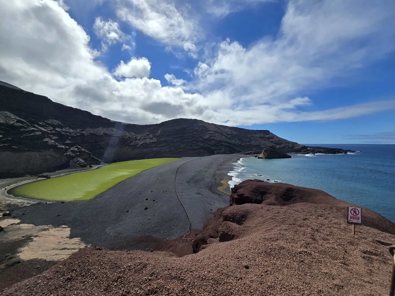 Lanzarote pálmafás, fekete homokos tengerpartja a kék óceán hullámaival
